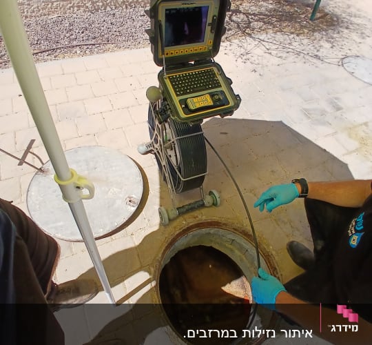 מכשיר איתור נזילות עם מסך ליד פתח ביוב